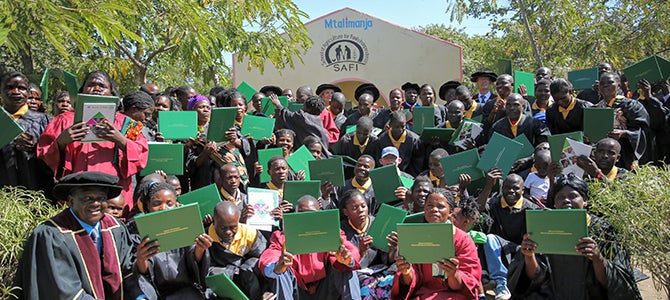 SAFI graduates hold their certificates up as they pose for a picture.